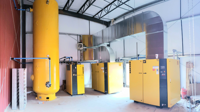 Kaeser industrial air compressors and dryers installed in a facility, featuring yellow equipment labeled CSD 100, SECOTEC TF 340 dryer